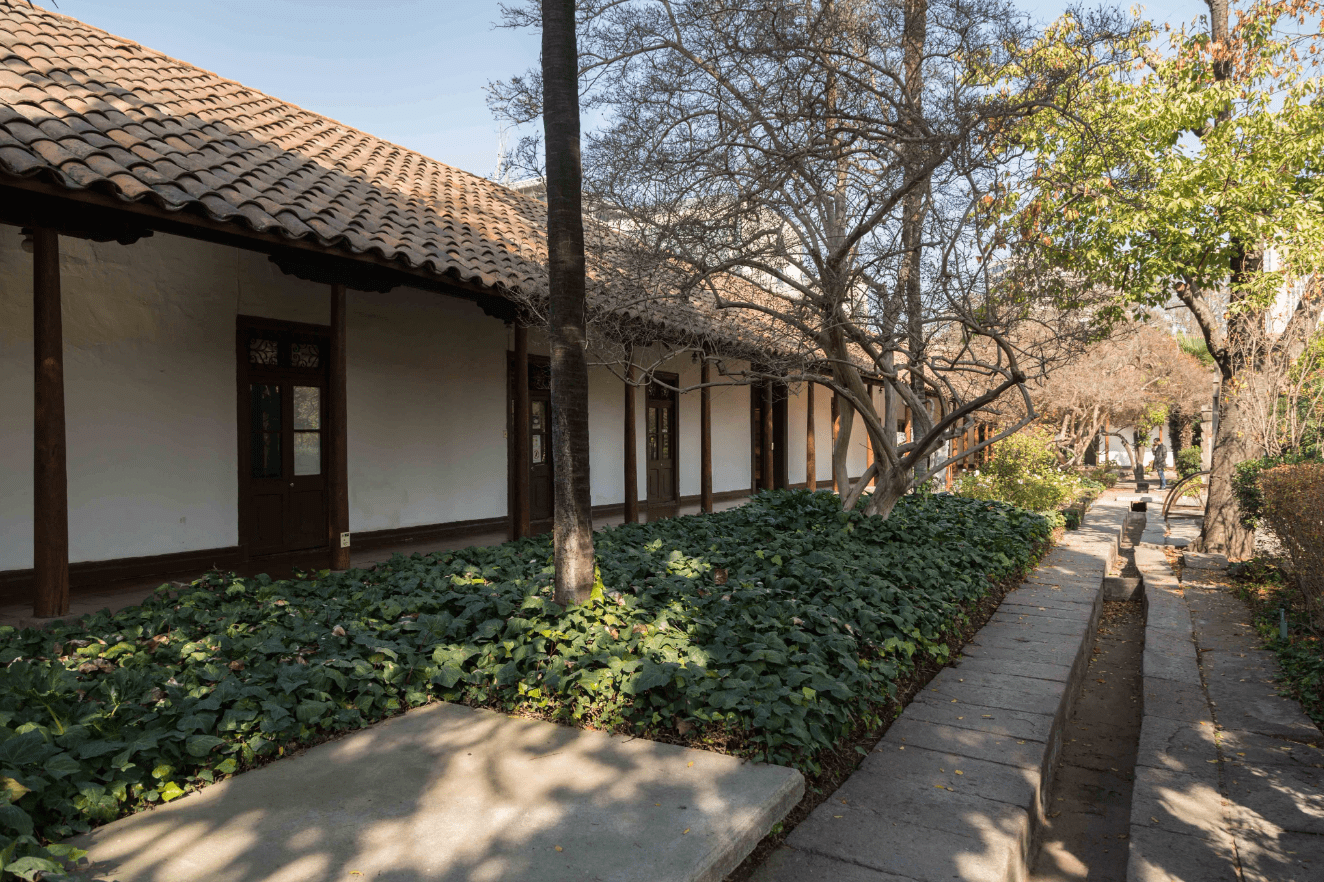 Fotografía del Centro de Patrimonio Cultural de la UC, en donde se aprecia el frontis, un patio y árboles.
