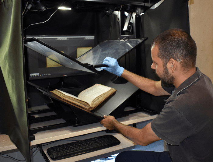 Fotografía que muestra a una persona realizando la digitalización de un libro antiguo.