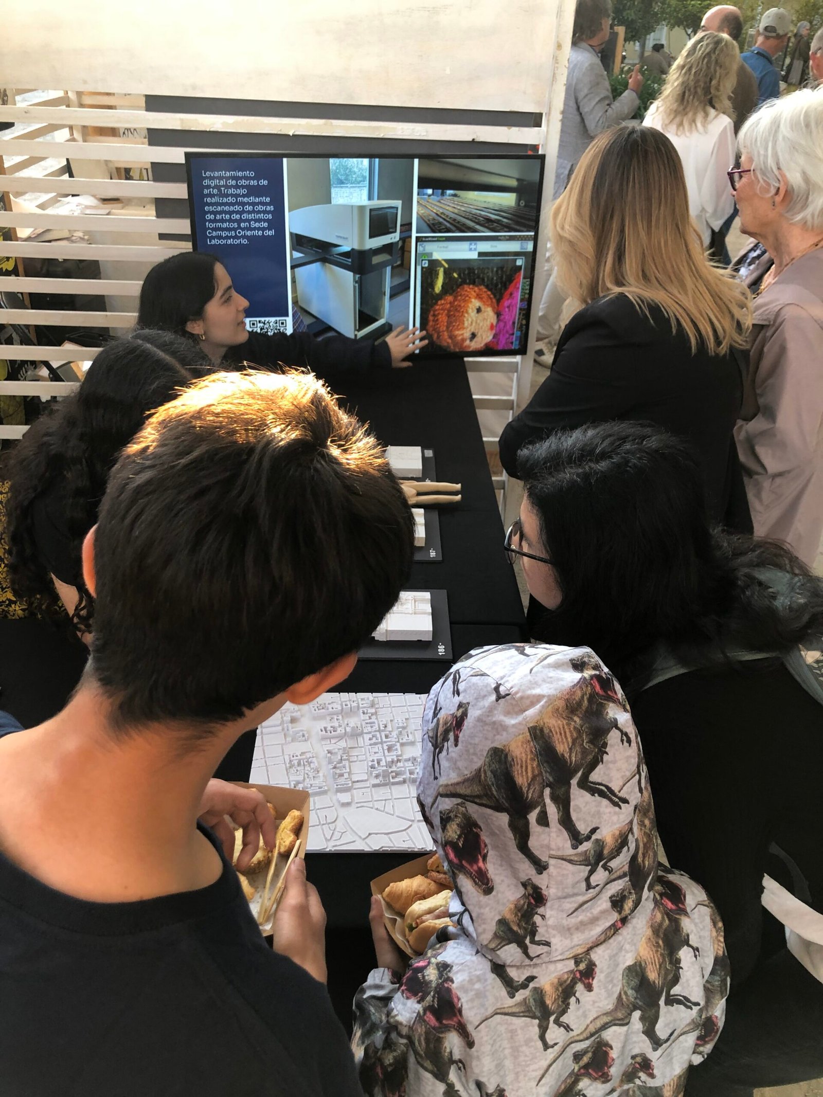 Se aprecian seis personas observando el stand del Laboratorio de Patrimonio Documental y escuchando a una integrante del equipo.